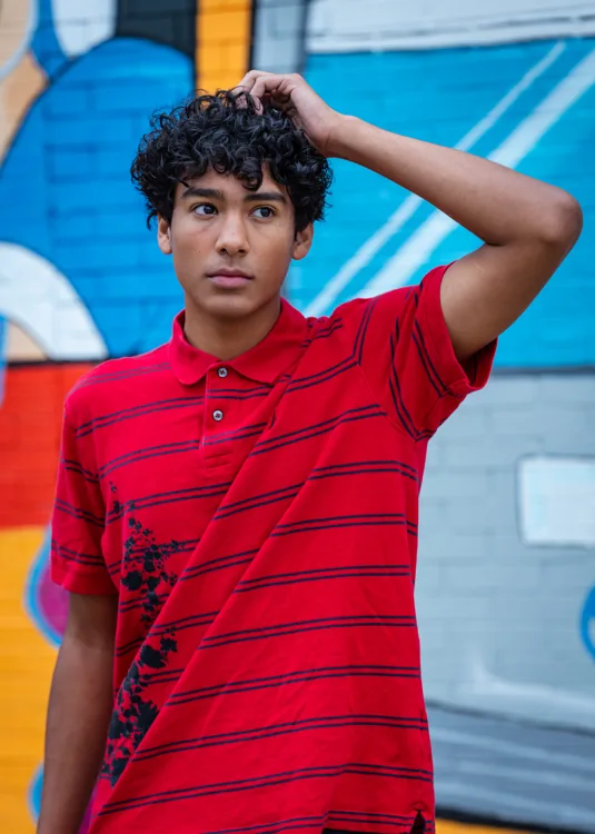 Senior portrait in a red polo against a blue mural