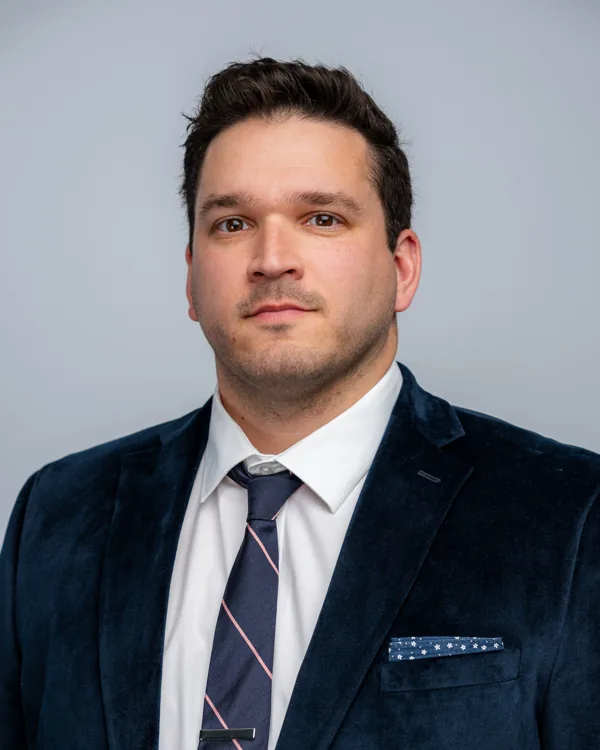 Studio headshot in a navy suit